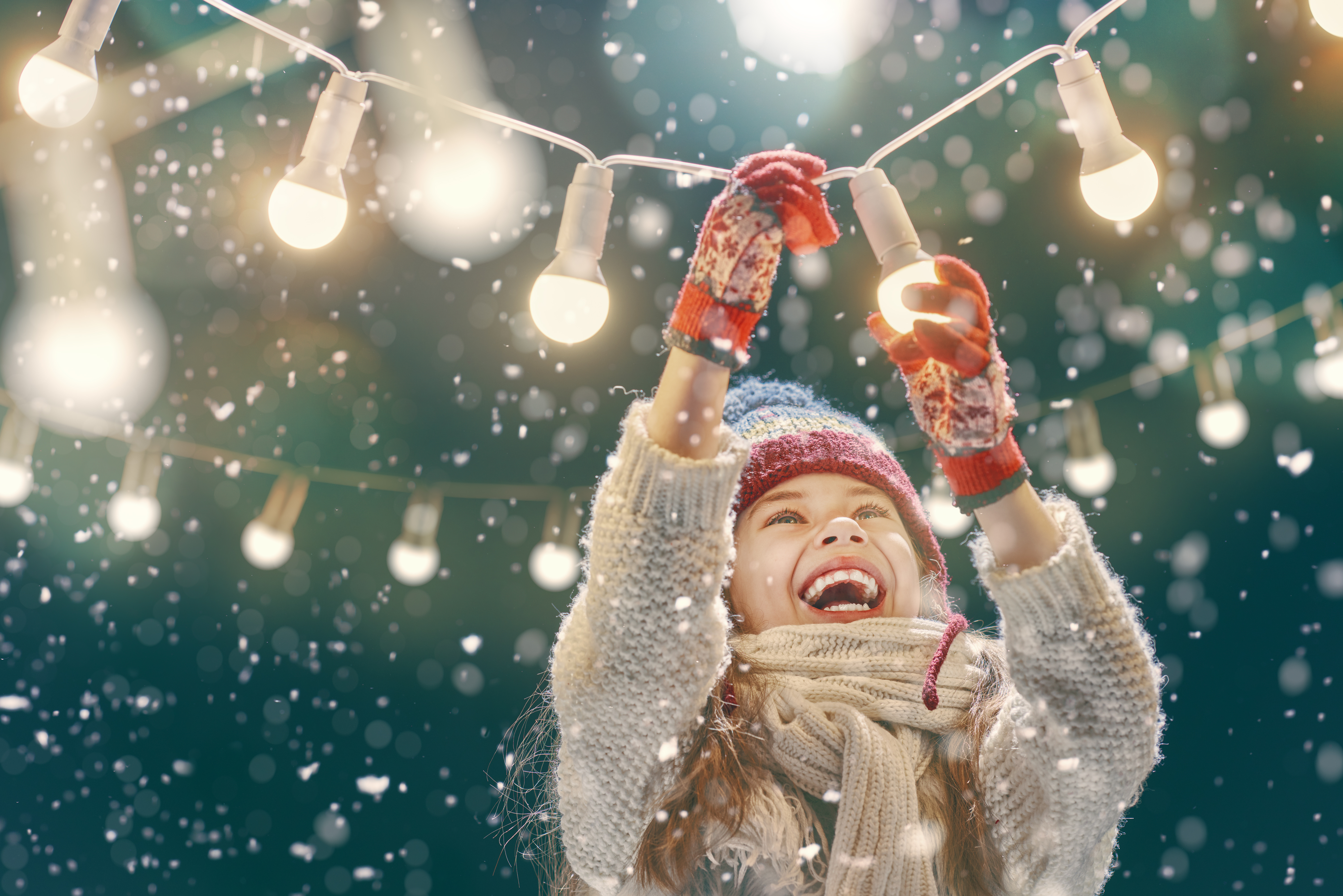 Person standing in a warehouse wearing a Santa hat and smiling and holding a small red heart