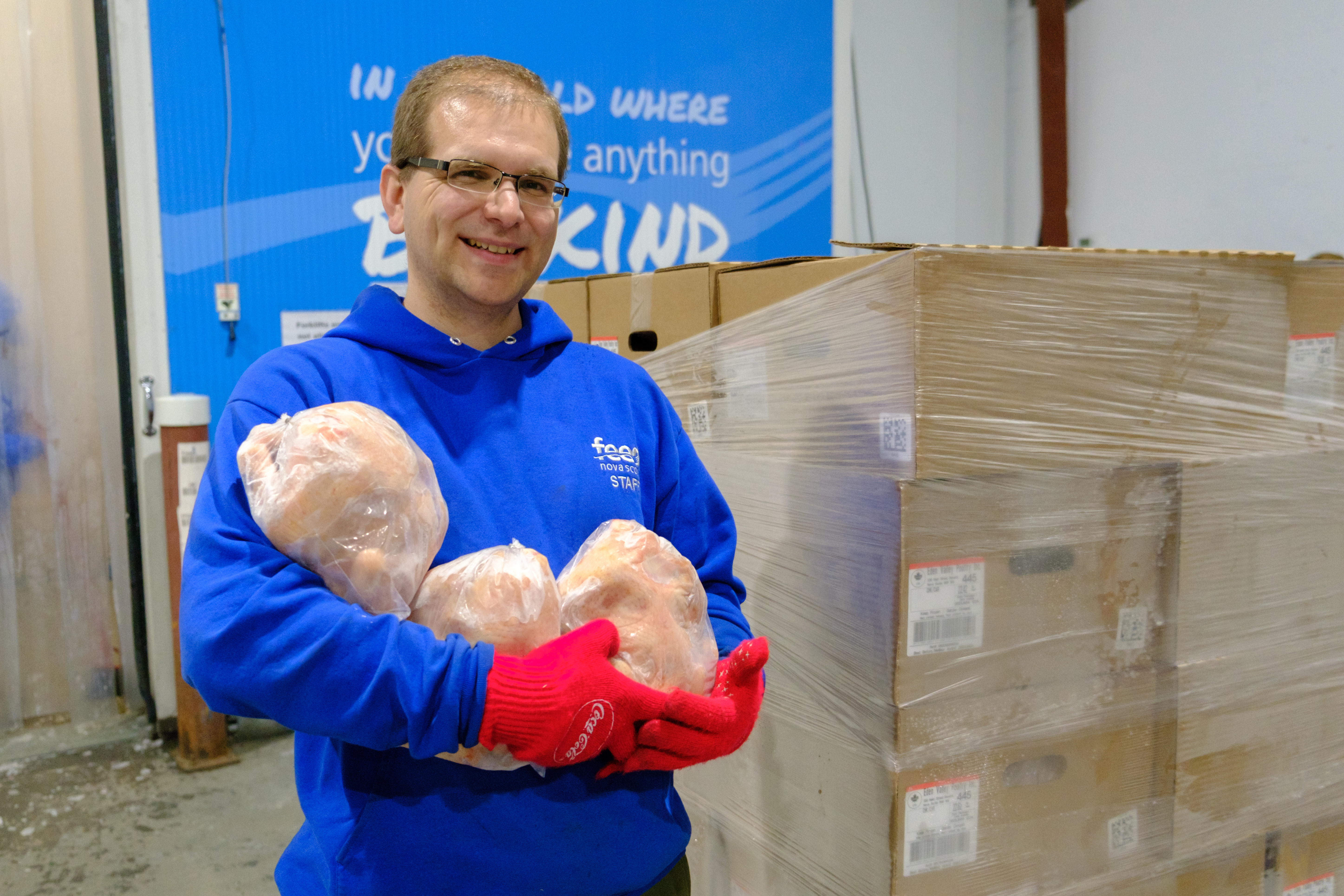 Feed Nova Scotia staff member holding frozen chickens that have been donated